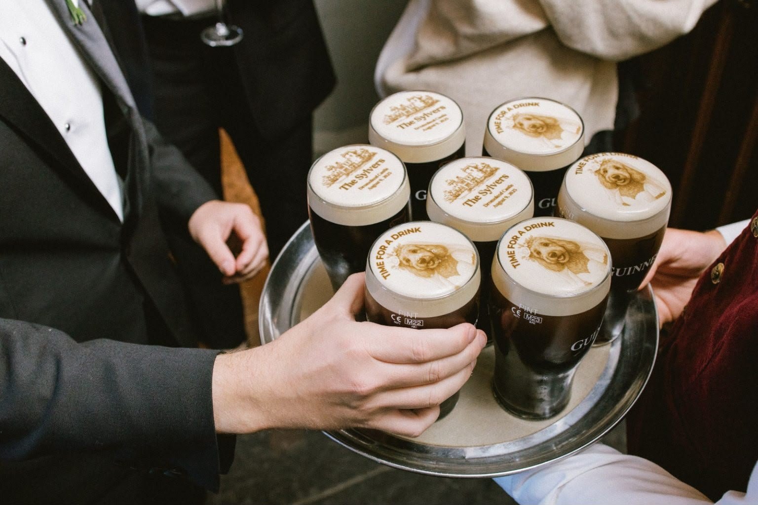 Guests reaching for Guinness pints printed with a wedding venue and a pet portrait