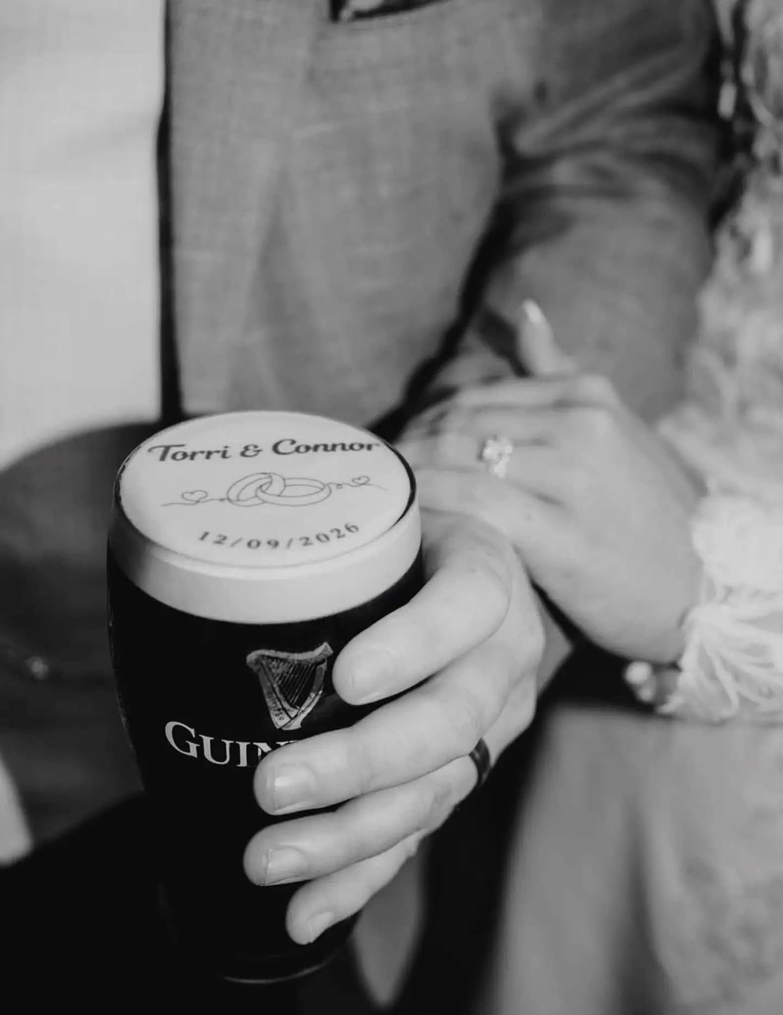 Newlyweds holding a pint printed with their names and wedding date